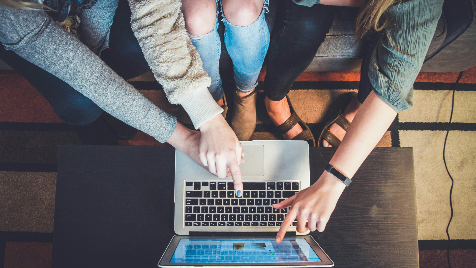 decorative: people huddled around a laptop pointing to something on it
